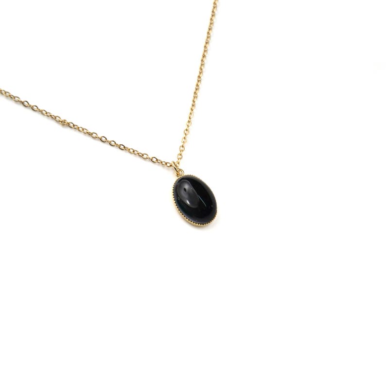 May include: A gold chain necklace with a black oval pendant.