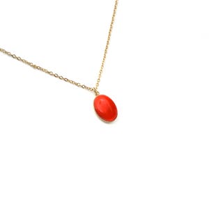 May include: A gold chain necklace with a red oval pendant.