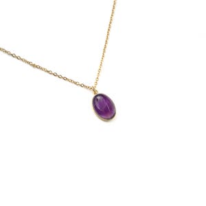 May include: A gold chain necklace with a purple oval amethyst pendant.