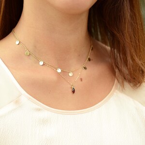 May include: A gold necklace with a red gemstone pendant and a layered chain with small gold circles.