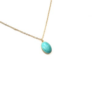 May include: A gold chain necklace with a turquoise oval pendant.