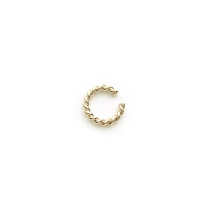 May include: A gold-toned twisted ear cuff. The cuff is made of a thick, twisted wire and is designed to be worn on the upper part of the ear.