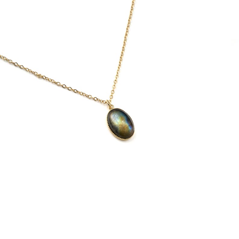 May include: A gold chain necklace with a silver oval pendant featuring a dark blue and green gemstone.