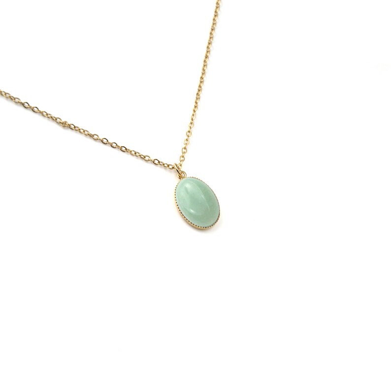 May include: A gold chain necklace with a light green oval pendant.