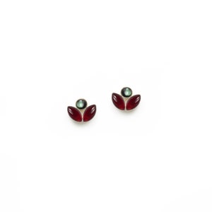 May include: A pair of gold earrings with red and green gemstone accents. The earrings are shaped like a flower with three petals.