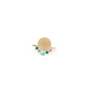 May include: A gold-colored ring with a textured, circular centerpiece and a row of colorful, round gemstones. The gemstones are in shades of green, purple, and turquoise. The ring is set against a white background.
