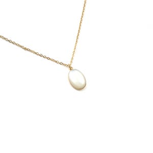 May include: A gold chain necklace with a white oval pendant.