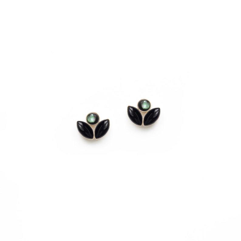 May include: A pair of black and green flower-shaped earrings with a green gemstone in the centre.