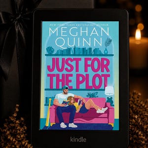 Puede incluir: Un lector electrónico Kindle negro que muestra la portada del libro Just for the Plot de Meghan Quinn. La portada presenta una ilustración de dos personas leyendo en un sofá rosa frente a una estantería, con el título en letras rosas grandes.