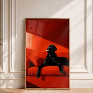 Op de afbeelding: Een ingelijste rechthoekige wandkunstprint met een zwarte Labrador-hond die op een felrode bank ligt. De hond heeft een sigaret in de bek met een dunne sliert rook die opstijgt. De scène is ondergedompeld in dieprode tinten met schuin licht.