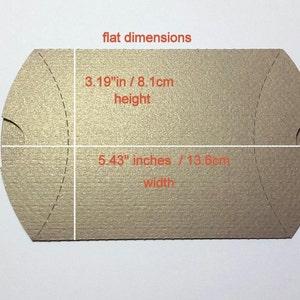 Peut inclure: Une bo&icirc;te &agrave; drag&eacute;es rectangulaire plate, de couleur brun clair, avec un dessus et un dessous incurv&eacute;s. La bo&icirc;te mesure 13,8 cm de large et 8,1 cm de haut.