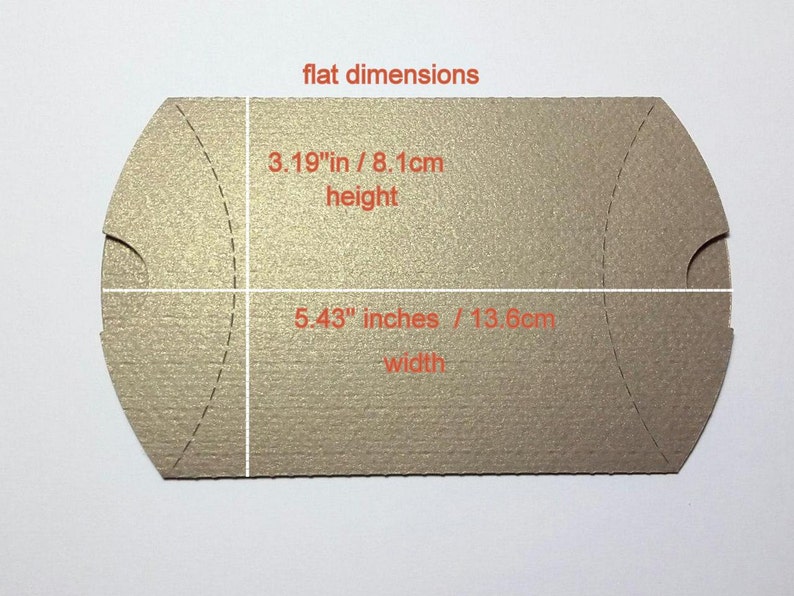 Peut inclure: Une bo&icirc;te &agrave; drag&eacute;es rectangulaire plate, de couleur brun clair, avec un dessus et un dessous incurv&eacute;s. La bo&icirc;te mesure 13,8 cm de large et 8,1 cm de haut.