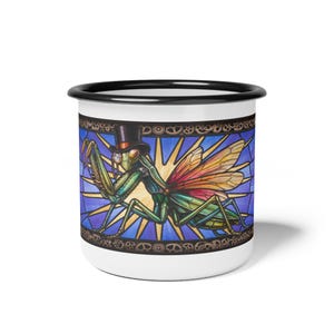 Puede incluir: Una taza de esmalte blanca con borde negro que presenta una ilustración colorida de una mantis religiosa con sombrero de copa y monóculo. La mantis está sobre un fondo azul y amarillo con rayos de sol y un borde de engranajes de color metálico.