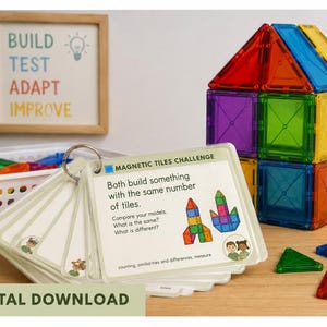 May include: A set of magnetic tiles challenge cards on a metal ring, featuring text and illustrations. A house structure built from colourful translucent magnetic tiles sits nearby, along with loose individual tiles and a white plastic storage basket.