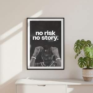 May include: A black and white framed wall art print featuring a person wearing a jersey and white wristbands, with the text "no risk no story." centered in white capital letters above the figure. The print is displayed in a thin black frame.