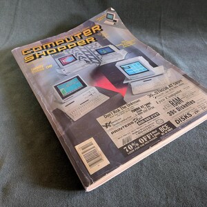 Op de afbeelding: Een vintage Computer Shopper tijdschrift met een cover waarop meerdere desktopcomputers staan afgebeeld, dikgedrukte gele en zwarte tekst, en diverse advertenties voor computerhardware, RAM en diskettes op de voorzijde.