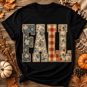 May include: A black short-sleeved t-shirt featuring the word FALL in large block letters. Each letter has a distinct pattern: the F has blue leaves, the A has blue floral motifs, the L has red and white gingham, and the L has blue plaid with pumpkins.