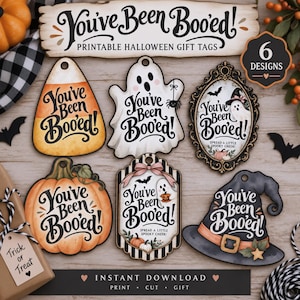 May include: Six printable Halloween gift tags featuring the text You've Been Booed. Designs include a candy corn, a ghost, an ornate framed ghost, a pumpkin, a ghost with a pink bow, and a witch hat. Each tag has a hole for hanging.