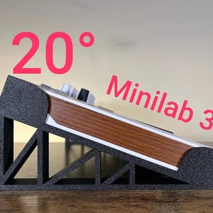 May include: A black, textured, triangular stand supporting a Minilab 3 keyboard controller at a 20-degree angle. The stand features a truss-like structural design, and the keyboard has a wood-grain side panel and white keys visible.