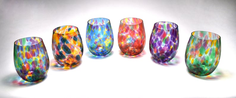 May include: Six colorful glass tumblers with a speckled pattern. Each tumbler has a different color base with a mix of colorful speckles.