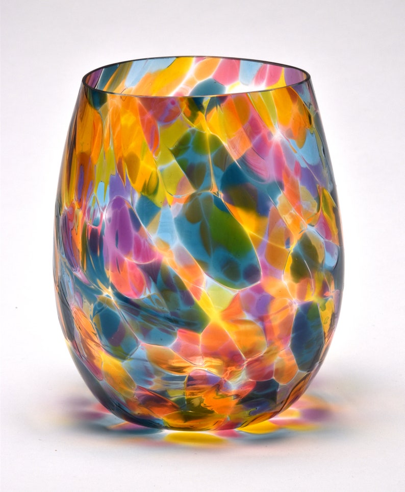 May include: A colorful glass vase with a swirling pattern of blue, yellow, pink, and green. The vase is made of clear glass with a textured surface.