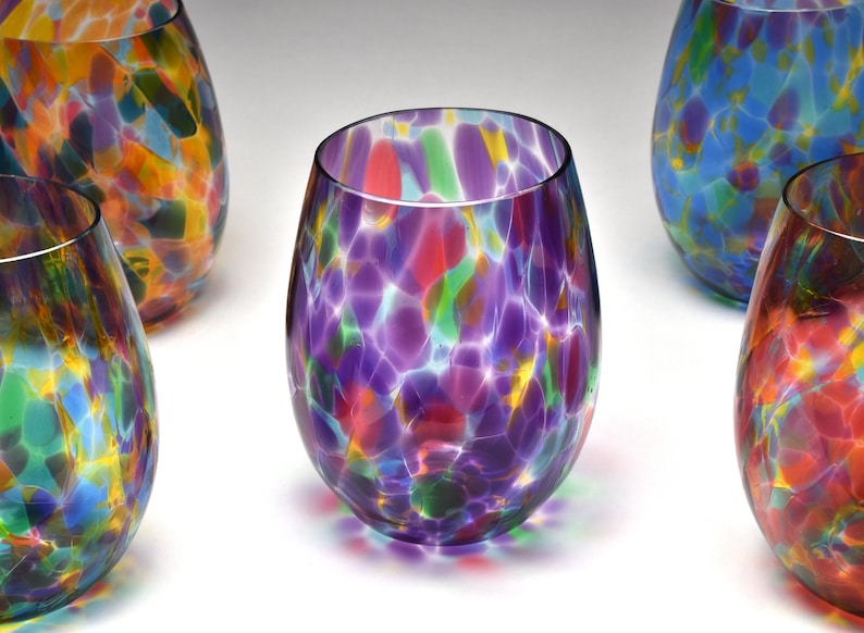 May include: Set of five colorful glass tumblers with a speckled pattern. Each tumbler has a different color scheme, including purple, blue, red, and yellow.