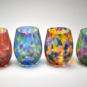 May include: Set of four colorful glass wine glasses with a speckled pattern. Each glass has a different color base, including red, blue, yellow, and green.