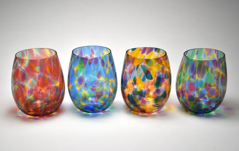 May include: Set of four colorful glass wine glasses with a speckled pattern. Each glass has a different color base, including red, blue, yellow, and green.