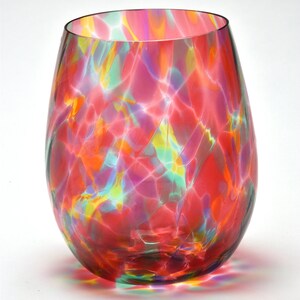 May include: A colorful glass wine glass with a swirling pattern of red, pink, green, and yellow. The glass has a rounded bottom and a wide opening.