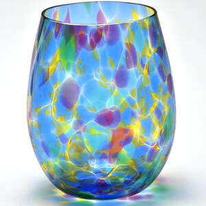 May include: A blue glass wine glass with a colorful, marbled pattern. The glass has a round, wide base and a narrow opening.