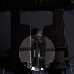 May include: A black aircraft throttle quadrant featuring two vertical levers with a central circular highlight. The base displays printed text including FLX, MCT, and CL, with a numerical scale visible at the bottom centre of the control unit.