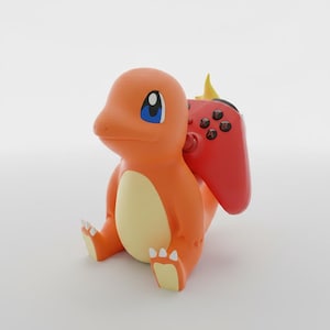 May include: An orange and cream-colored figurine of a bipedal creature with a flame on its tail, designed as a controller stand. The figurine features large blue eyes and white claws, holding a red video game controller against its back.