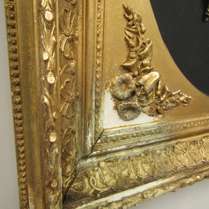 Puede incluir: Primer plano de un marco de imagen pintado de oro con detalles ornamentados. El marco est&aacute; astillado y muestra signos de edad. El marco est&aacute; hecho de madera y tiene un fondo negro.