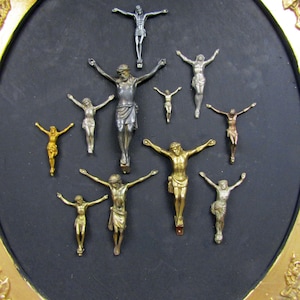 Puede incluir: Una colecci&oacute;n de 10 peque&ntilde;os crucifijos de metal plateado y dorado dispuestos en forma de tri&aacute;ngulo sobre un fondo negro. Los crucifijos son de diferentes tama&ntilde;os y estilos, y algunos tienen un dise&ntilde;o m&aacute;s ornamentado que otros.