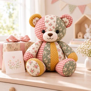 Pode incluir: Um urso de peluche de patchwork feito de v&aacute;rios padr&otilde;es de tecido, incluindo xadrez vichy vermelho, bolinhas amarelo-mostarda e estampas florais em tons de verde, rosa e branco. O urso tem olhos redondos escuros e nariz e boca castanhos bordados.