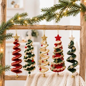 May include: Five spiral-shaped Christmas tree ornaments made of crocheted yarn. Each ornament features a star at the top and hangs from a gold string. The trees are decorated with small beads, bells, miniature gift boxes, and snowflake accents.