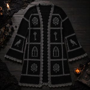 Könnte beinhalten: Eine schwarze Häkelstrickjacke mit langen Glockenärmeln und einem grauen Bogenkantenabschluss. Das Kleidungsstück besteht aus quadratischen Feldern mit detaillierten grauen Stickereien von Rosen, Schlüsseln, gotischen Fenstern und Raben.