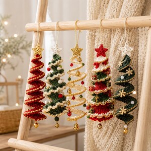 May include: Five spiral-shaped Christmas tree ornaments made of crocheted yarn, each topped with a star. The trees feature various colors including red, green, and cream, decorated with small bells, miniature gift boxes, and snowflake accents.