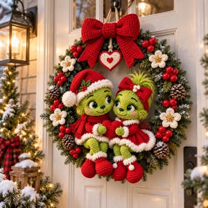 May include: A Christmas wreath featuring two green crocheted figures wearing red and white outfits, adorned with a large red crocheted bow, a heart-shaped ornament, white flowers, red berries, and pinecones, all mounted on a green pine branch base.