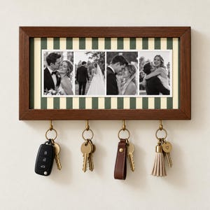 May include: A rectangular wooden wall-mounted key holder featuring a frame with a green and cream vertical striped background. It displays four black and white wedding photographs and includes four brass hooks holding various keys and keychains.