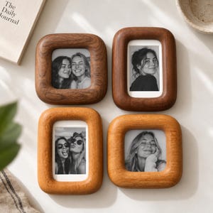 May include: Four rectangular wooden picture frames with rounded corners, each containing a black and white photograph. Two frames are made of dark brown wood, and two frames are made of a lighter, honey-toned wood, all featuring visible wood grain.