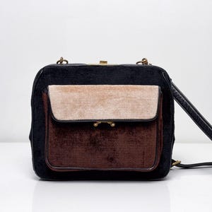 May include: A vintage handbag with a rectangular shape. The bag features a black velvet body with a tan and brown velvet front pocket. It has a gold clasp and a black shoulder strap.