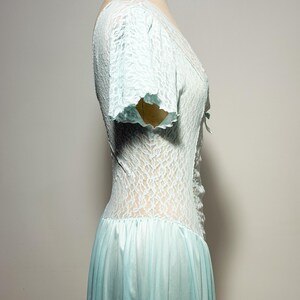 May include: A light blue dress featuring a lace bodice with short sleeves and a V-neckline. The bodice has a central lace-up detail with a small bow. The skirt is made of a smooth, solid-colored fabric that flows from the waistline downward.