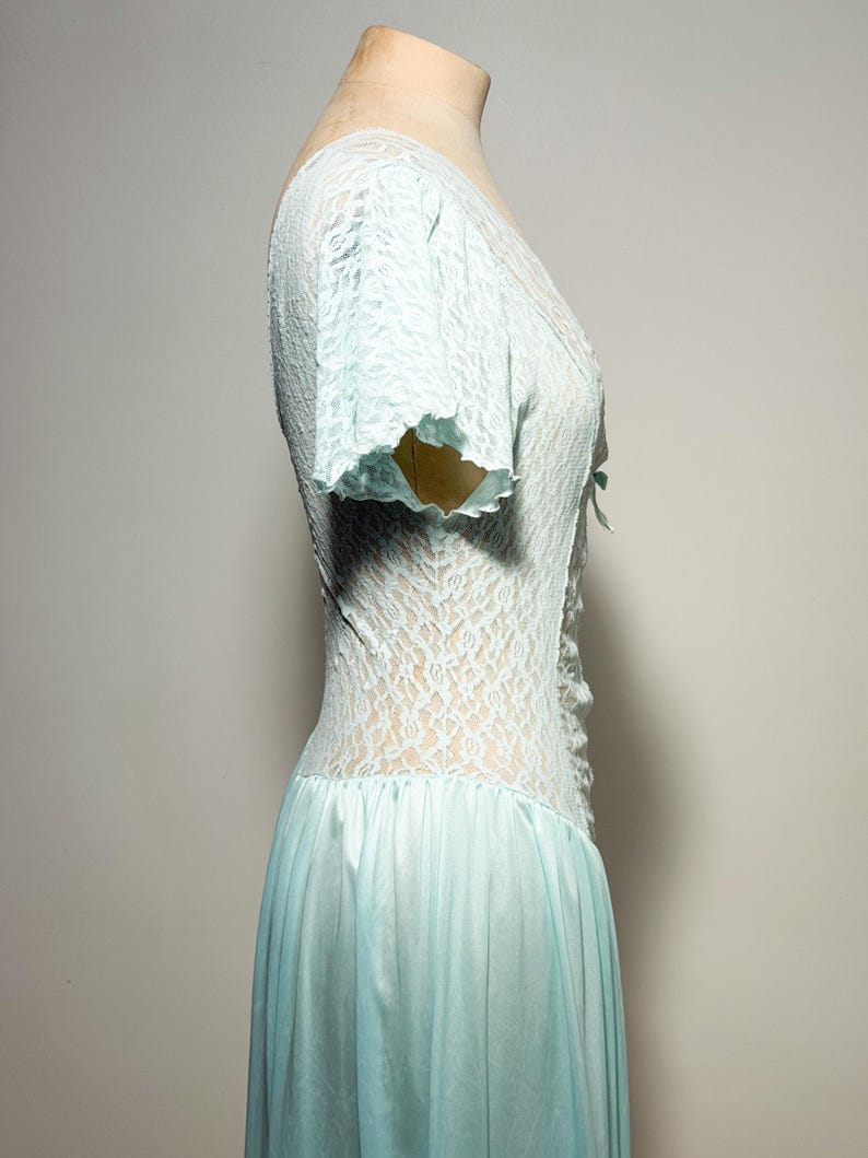 May include: A light blue dress featuring a lace bodice with short sleeves and a V-neckline. The bodice has a central lace-up detail with a small bow. The skirt is made of a smooth, solid-colored fabric that flows from the waistline downward.