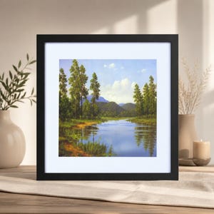 Peut inclure: Une impression d'art encadrée carrée représentant un paysage de rivière calme traversant une forêt verte avec de grands arbres et des collines sous un ciel bleu clair avec des nuages blancs, dans un cadre noir simple avec un passe-partout blanc.