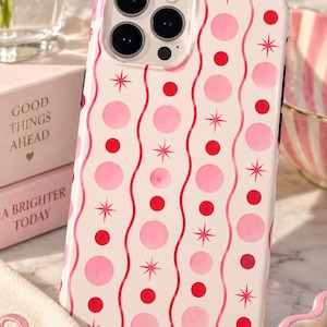 May include: A phone case with a cream background featuring a repeating pattern of vertical wavy pink lines, alternating solid red circles, light pink circles, and small red starburst icons. The case has a cutout for a triple camera lens system.