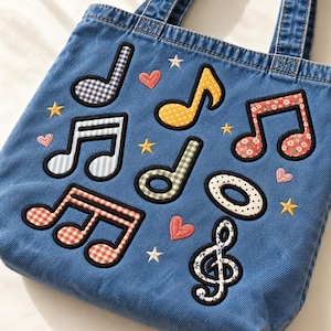May include: A blue denim tote bag featuring embroidered musical note patches in various patterns including gingham, polka dots, and floral prints. The design is accented with small embroidered pink hearts and yellow and white stars.
