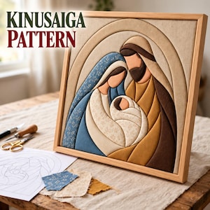 May include: A Kinusaiga pattern framed art piece depicting a nativity scene with fabric-covered foam shapes in blue, tan, and brown. The figures are stylized with smooth curves and floral fabric accents, set within a light wood frame.