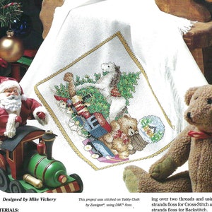 May include: Cross stitch pattern for a nursery time Christmas scene with a toy train, a teddy bear, and a small white stuffed animal. The pattern is called "Old Fashioned Christmas" and is from the "Cross Stitch Collectors Series".
