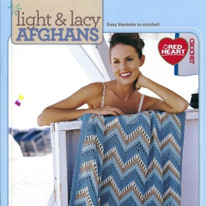 May include: A woman is sitting on a white wooden bench with a blue, white, and brown crocheted blanket. The blanket has a chevron pattern. The text "light & lacy AFGHANS" is at the top of the image. The text "Easy blankets to crochet!" is below the title. The text "RED HEART" is in a red heart shape. The text "CROCHET" is to the right of the heart.